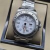 Rolex — esfera blanca con aguja naranja y bisel numerado plateado