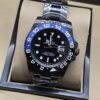 Rolex — esfera negra con bisel negro y azul, brazalete plateado