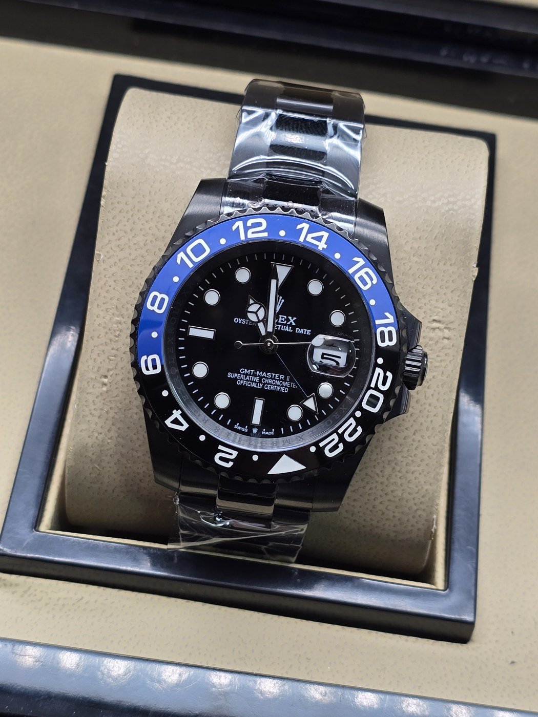 Rolex — esfera negra con bisel negro y azul, brazalete plateado
