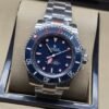 Rolex — esfera azul oscura con detalles rojos y brazalete plateado