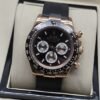 Rolex — esfera negra con subesferas claras, caja rosada y correa negra