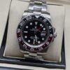 Rolex — esfera negra con bisel oscuro y rojo, brazalete plateado