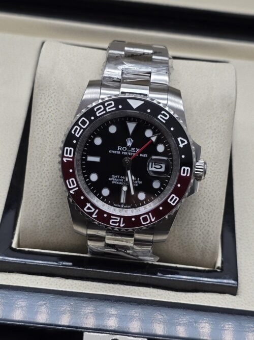 Rolex — esfera negra con bisel oscuro y rojo, brazalete plateado