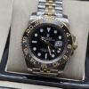 Rolex — esfera negra con numeración dorada y brazalete de eslabones bicolor