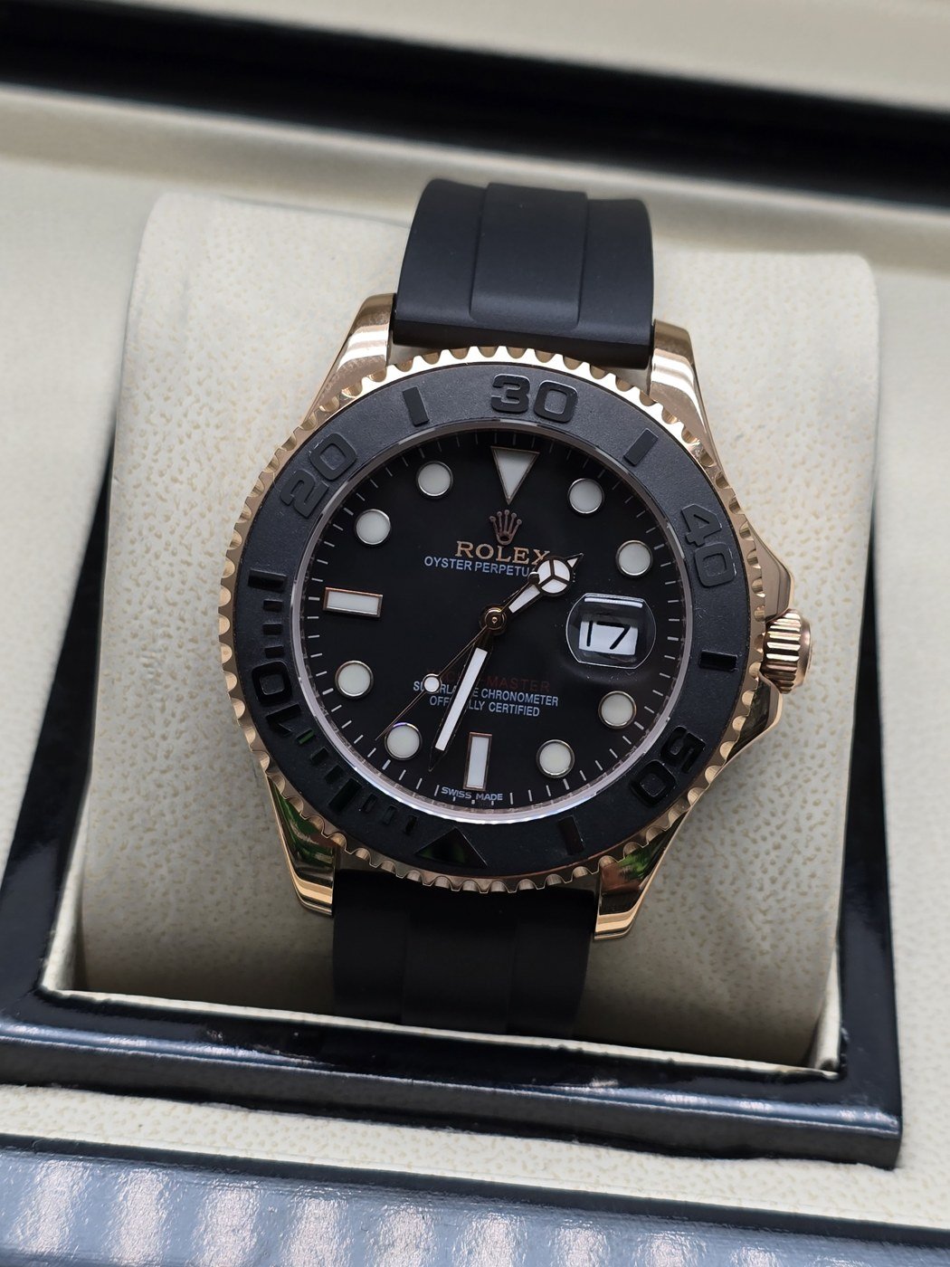 Rolex — esfera negra con bisel gris, caja rosada y correa negra