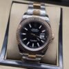 Rolex — esfera negra con bisel rosado estriado y brazalete bicolor · 41 mm