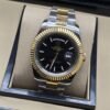 Rolex — esfera negra con bisel dorado estriado y brazalete bicolor · 41 mm