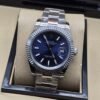 Rolex — esfera azul oscura con bisel estriado y brazalete plateado · 41 mm