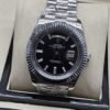 Rolex — esfera negra con números romanos y bisel estriado y brazalete plateado · 41 mm