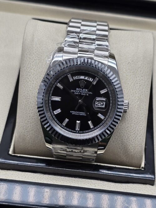 Rolex — esfera negra con números romanos y bisel estriado y brazalete plateado · 41 mm