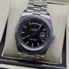 Rolex — esfera negra con índices claros y bisel estriado y brazalete plateado · 41 mm