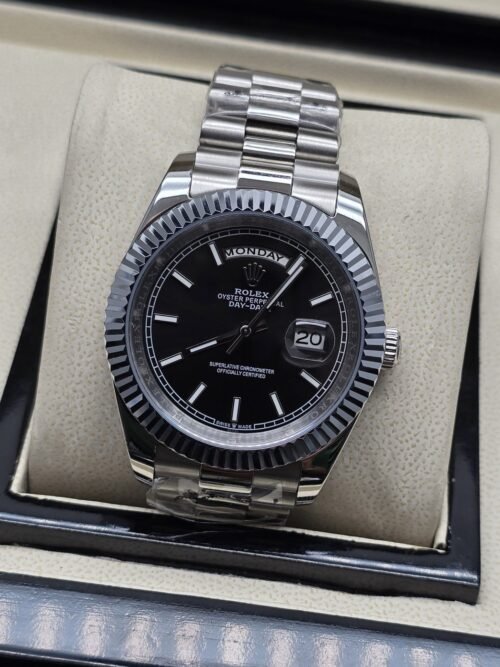 Rolex — esfera negra con índices claros y bisel estriado y brazalete plateado · 41 mm
