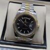 Rolex — esfera negra con índices claros y bisel dorado y brazalete bicolor · 41 mm