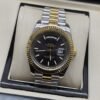 Rolex — esfera negra con bisel dorado y brazalete bicolor · 41 mm