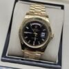Rolex — esfera negra con bisel dorado estriado y brazalete dorado · 41 mm