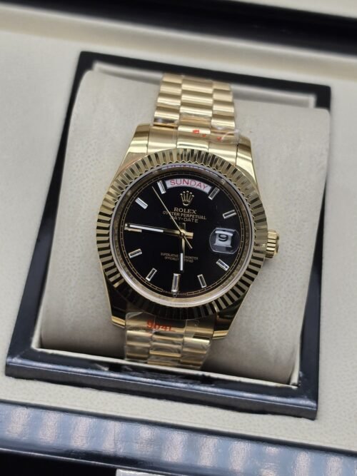 Rolex — esfera negra con bisel dorado estriado y brazalete dorado · 41 mm