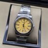 Rolex — esfera amarilla con bisel liso y brazalete plateado · 36 mm