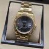 Rolex — esfera negra con bisel dorado estriado y brazalete dorado · 36 mm
