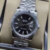 Rolex — esfera negra con números romanos y bisel estriado y brazalete plateado · 36 mm