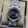 Rolex — esfera negra con bisel estriado y brazalete plateado · 36 mm