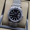 Rolex — esfera negra con números romanos y brazalete plateado · 36 mm