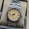 Rolex — esfera dorada clara con bisel liso y brazalete plateado · 36 mm