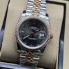 Rolex — esfera negra con bisel rosado estriado y brazalete bicolor · 36 mm