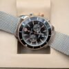 Breitling — cronógrafo con esfera negra, bisel negro con detalles oro rosa y brazalete de malla de acero