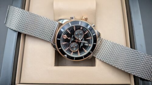 Breitling — cronógrafo con esfera negra, bisel negro con detalles oro rosa y brazalete de malla de acero