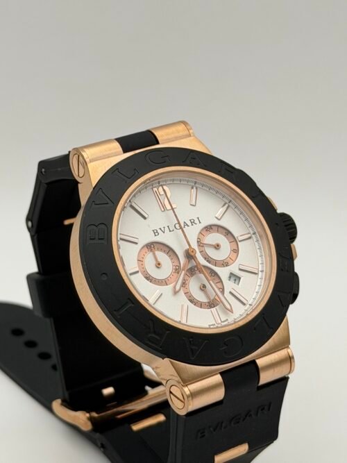 Bvlgari — cronógrafo con esfera blanca, caja oro rosa, bisel negro y correa de caucho negra