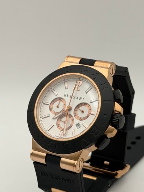 Bvlgari — cronógrafo con esfera blanca, caja oro rosa, bisel negro y correa de caucho negra