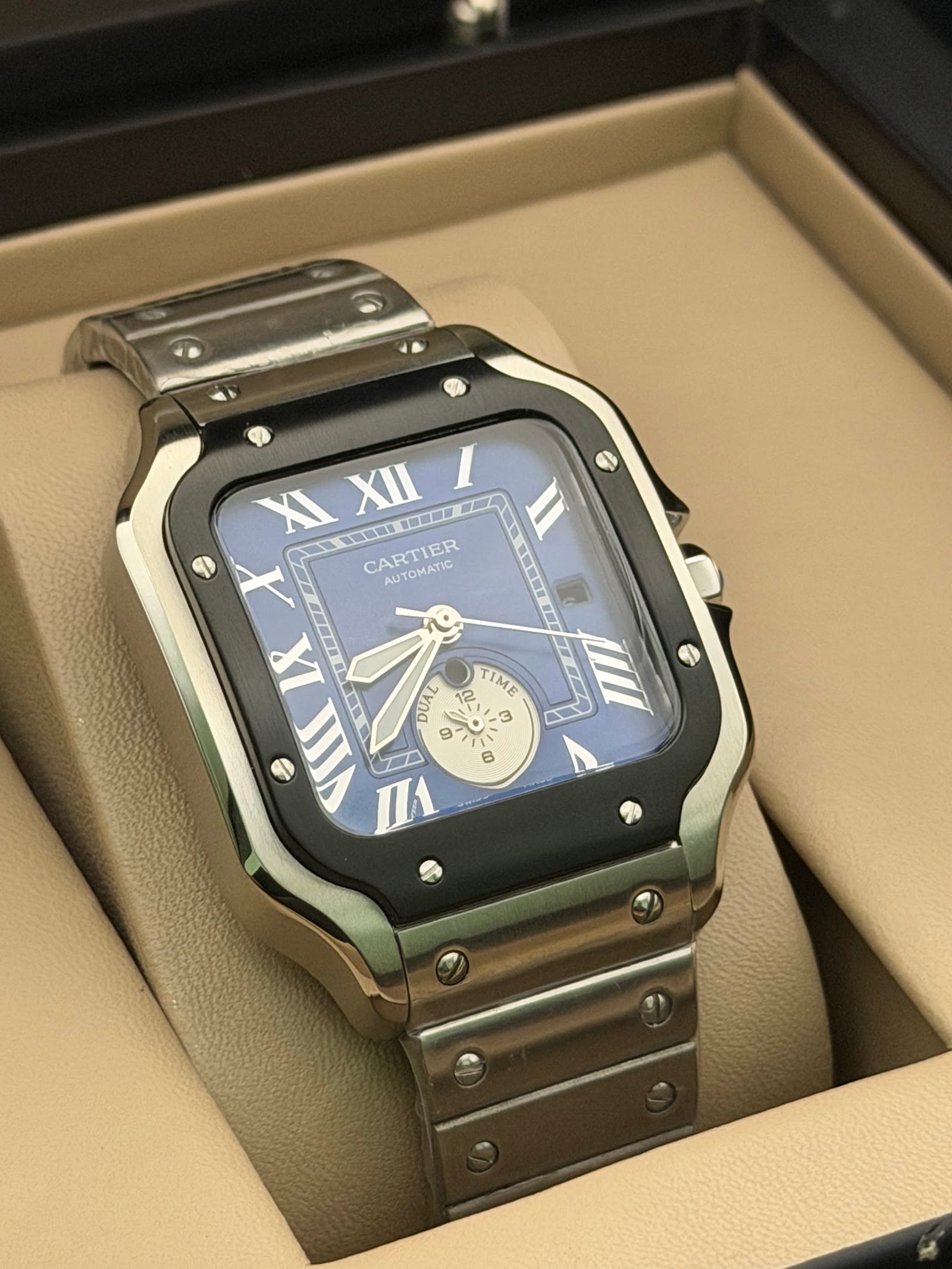 Cartier — caja cuadrada con bisel negro, esfera azul con volante a la vista y brazalete de acero