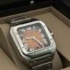 Cartier — caja cuadrada de acero, esfera naranja degradada con números romanos y brazalete de acero
