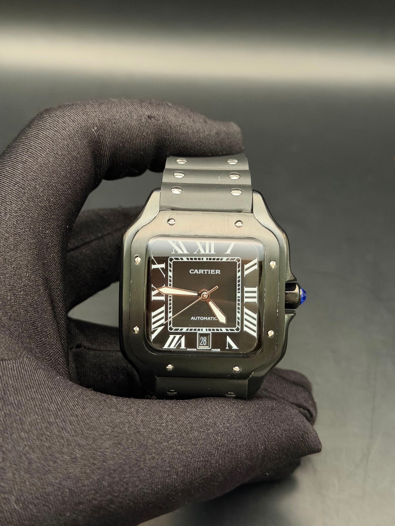 Cartier — caja cuadrada gris oscura, esfera negra con números romanos y brazalete gris oscuro