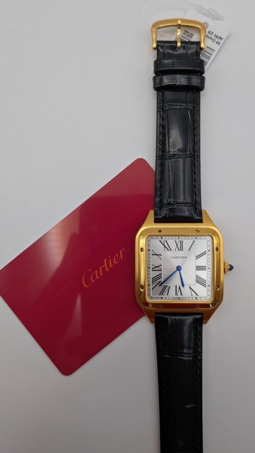 Cartier — caja rectangular dorada, esfera blanca con números romanos y correa de cuero negra