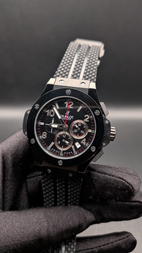 Hublot — cronógrafo negro con detalles rojos y correa de caucho negra con franja gris