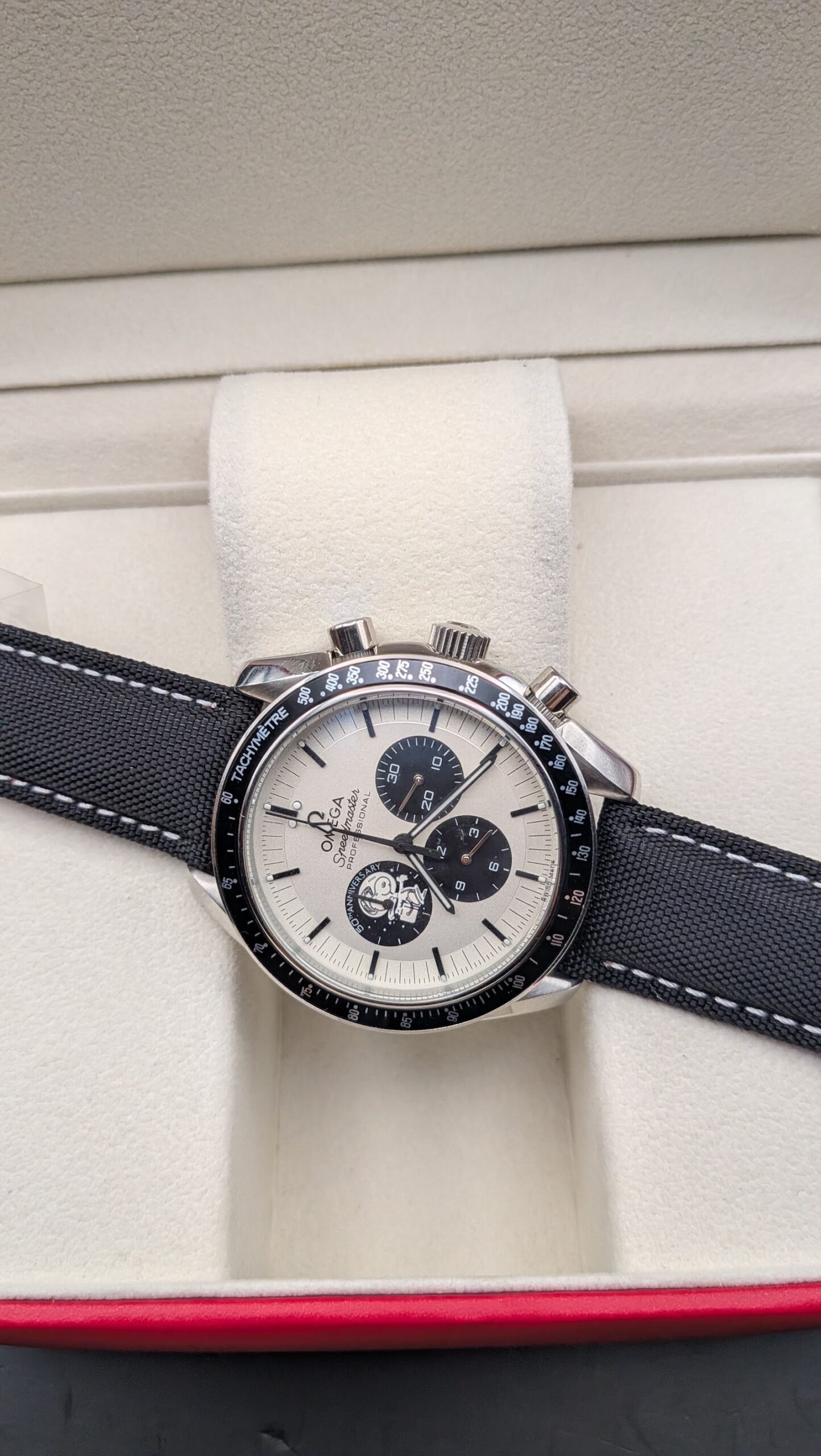 Omega — cronógrafo con esfera blanca y subesferas negras, caja de acero y correa de tela negra