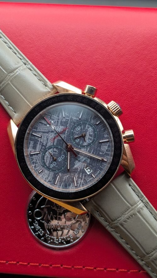 Omega — cronógrafo con esfera gris texturizada, caja oro rosa y correa de cuero gris