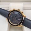 Omega — cronógrafo con esfera gris oscura, caja dorada y correa de tela negra