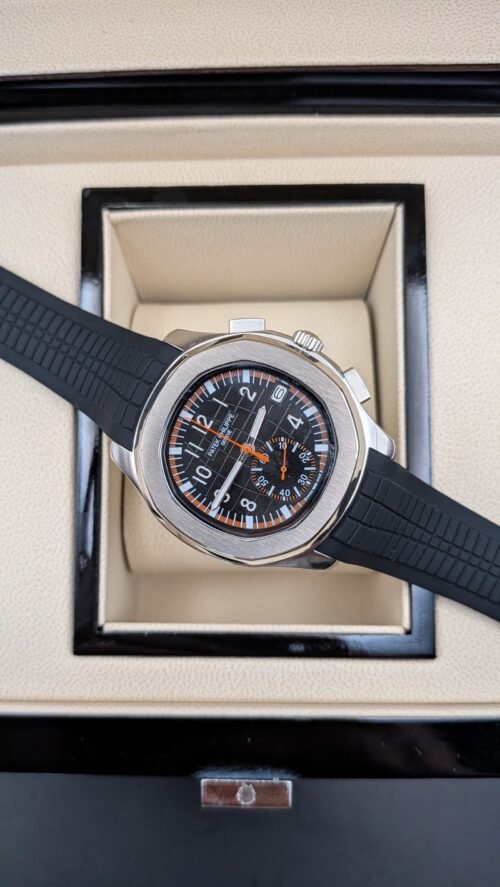 Patek Philippe — cronógrafo con esfera negra y detalles naranjas, caja de acero y correa de caucho negra
