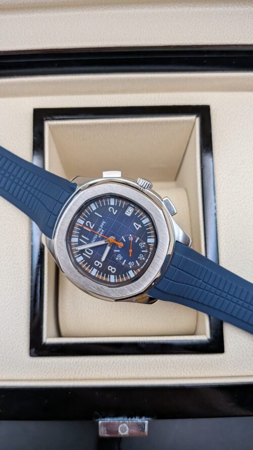 Patek Philippe — cronógrafo con esfera azul y detalles naranjas, correa de caucho azul