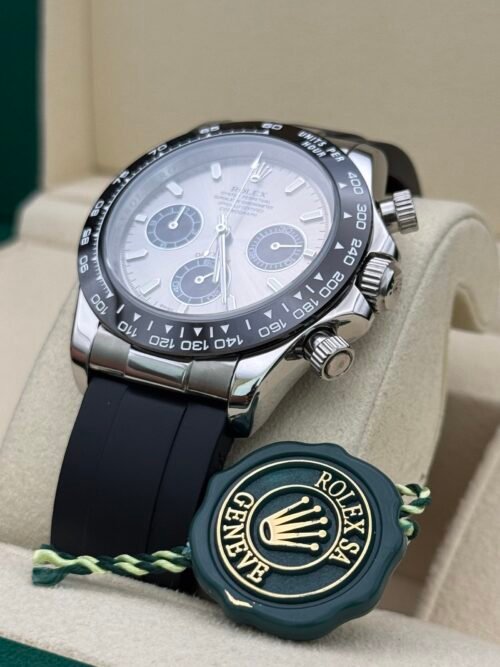 Rolex — cronógrafo con esfera plateada y subesferas negras, bisel negro y correa de caucho negra