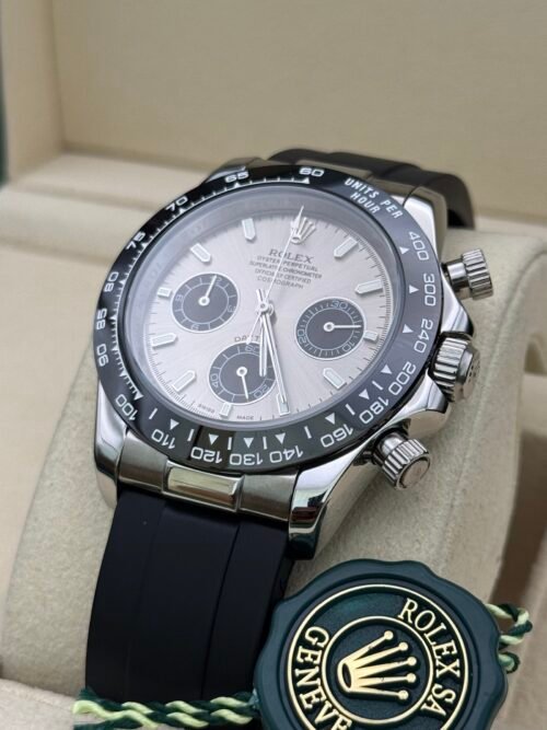 Rolex — cronógrafo con esfera plateada y subesferas negras, bisel negro y correa de caucho negra