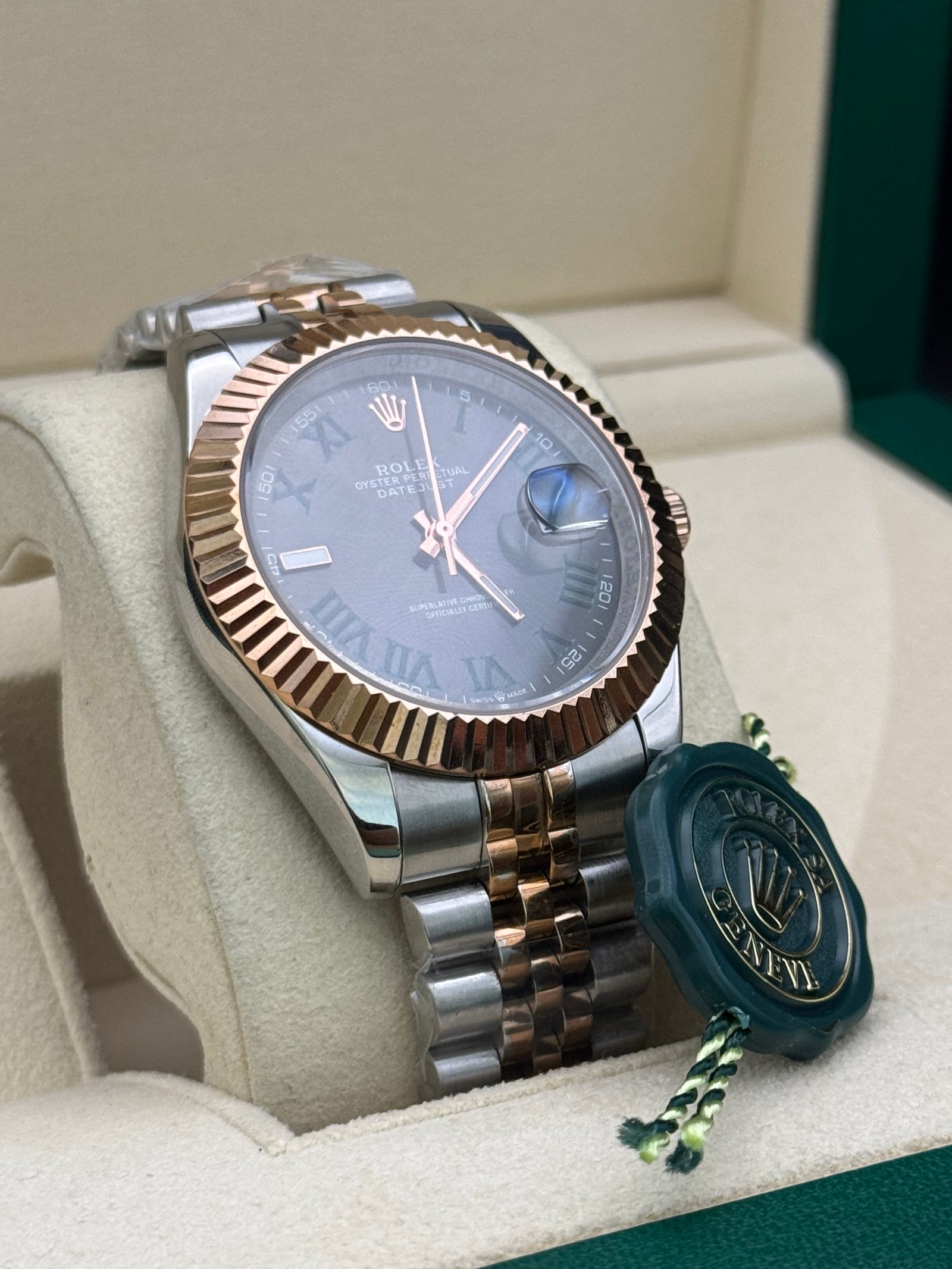 Rolex — esfera gris con números romanos, bisel oro rosa estriado y brazalete jubilee bicolor
