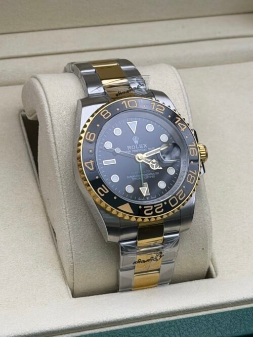 Rolex — esfera negra con doble huso horario, bisel dorado y negro y brazalete bicolor