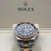 Rolex — esfera negra con doble huso horario, bisel dorado y negro y brazalete bicolor