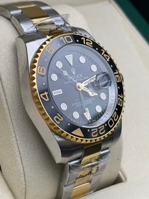 Rolex — esfera negra con doble huso horario, bisel dorado y negro y brazalete bicolor