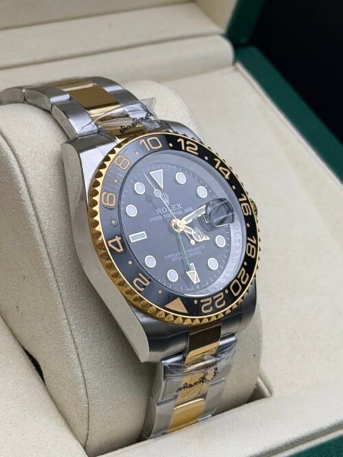 Rolex — esfera negra con doble huso horario, bisel dorado y negro y brazalete bicolor