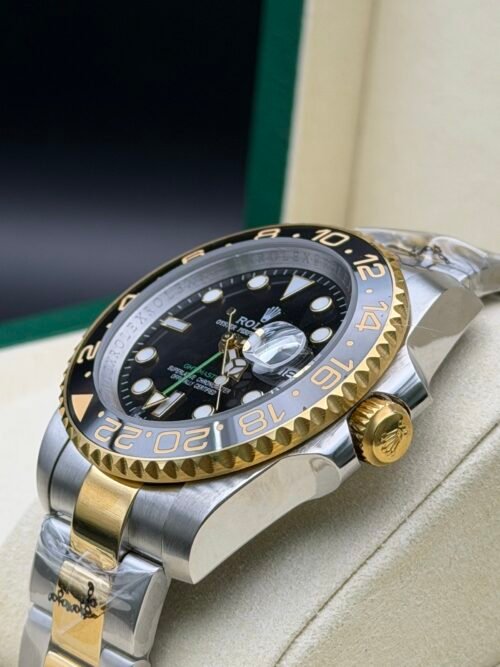 Rolex — esfera negra con doble huso horario, bisel dorado y negro y brazalete bicolor