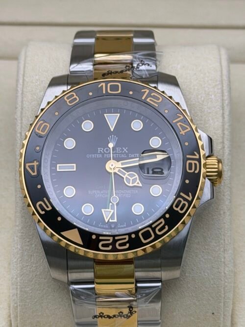 Rolex — esfera negra con doble huso horario, bisel dorado y negro y brazalete bicolor